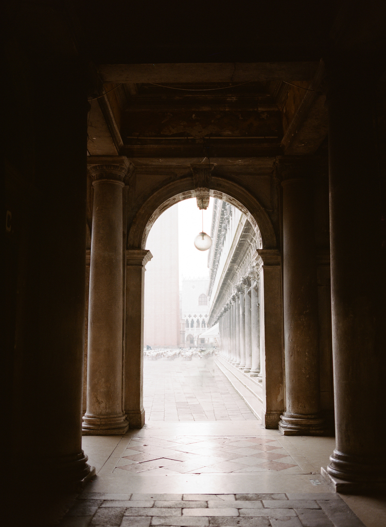 Long archway with tall pillars leading to the Piazza San Marco