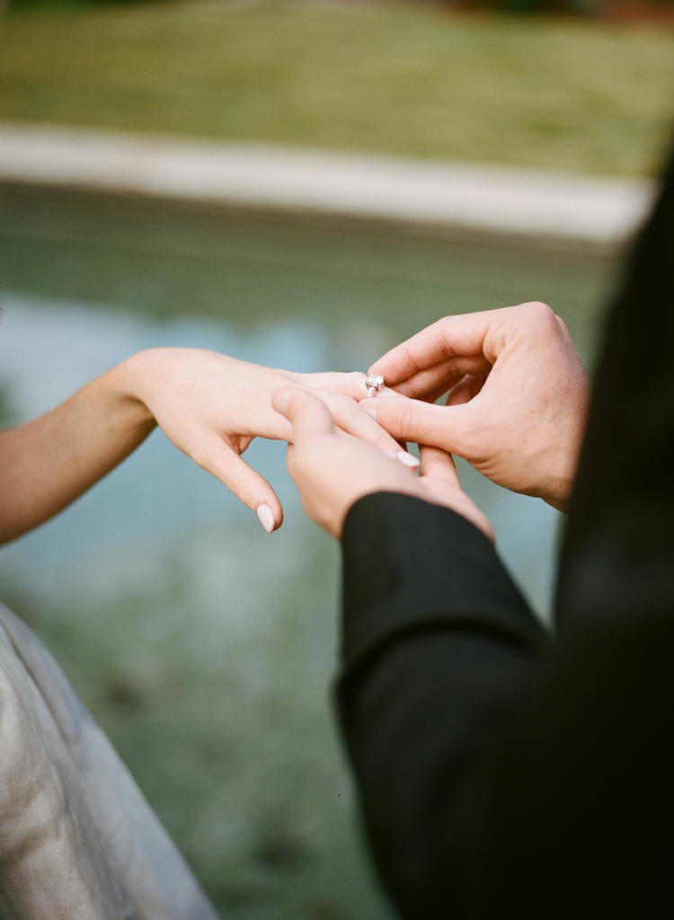Groom placing a wedding ring on his brides hand