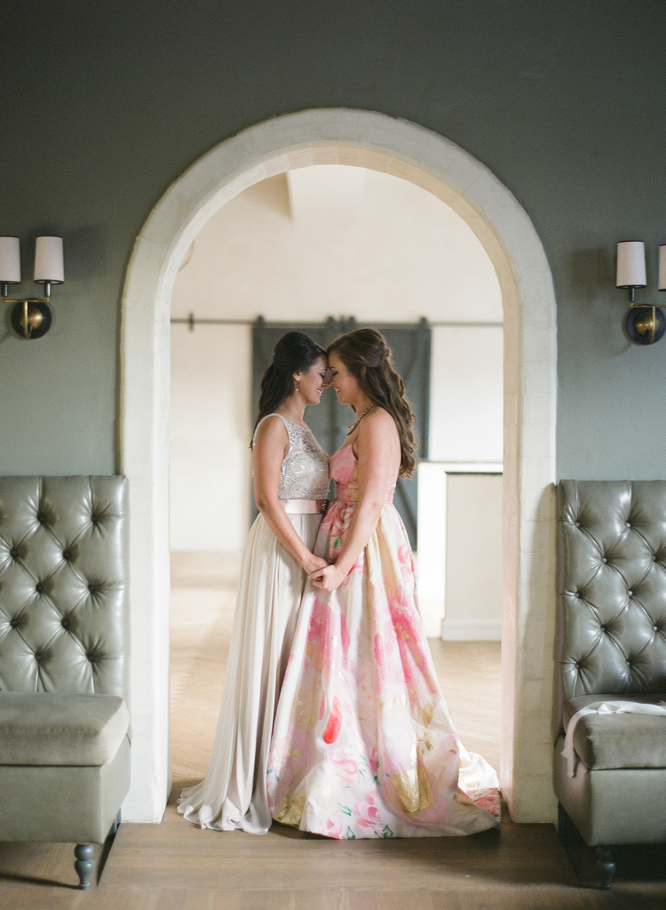Brides gazing in to each others eyes touching foreheads under an archway 