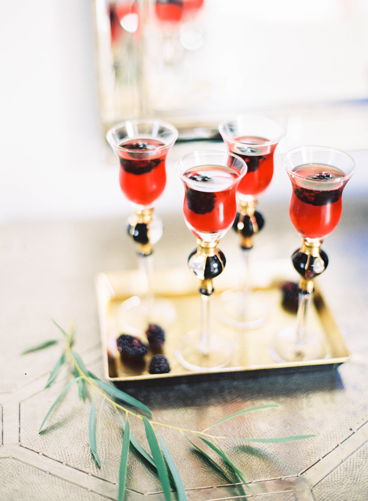 Specialty red cocktails with blackberries on a gold tray