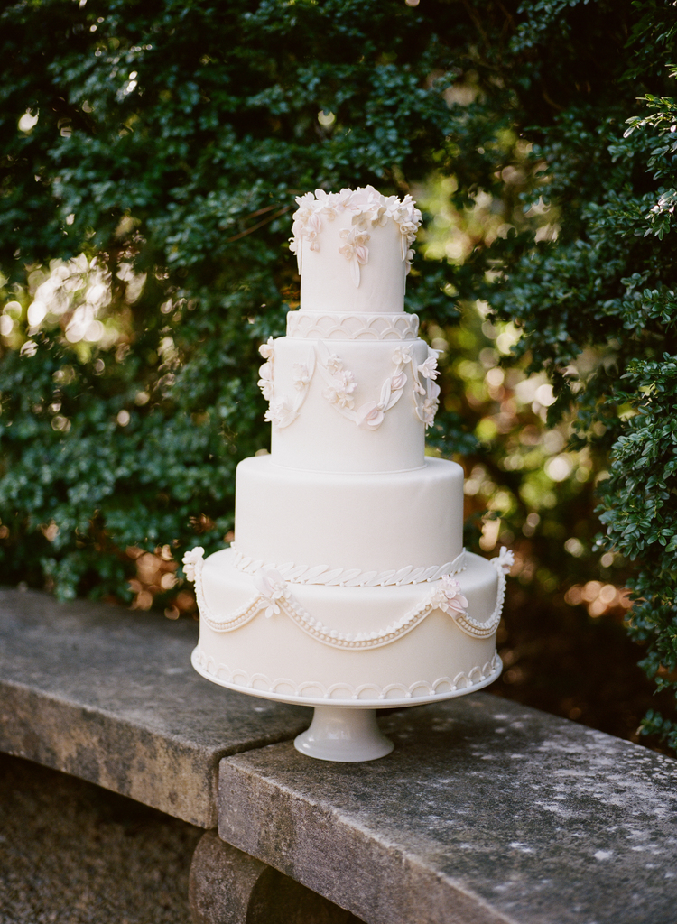 four tiered simple yet elegant white wedding cake with edible flowers and design 