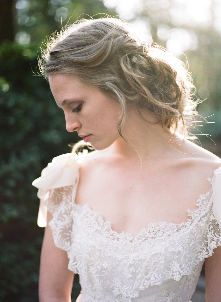 close up of a brides lace and beaded wedding gown with bows on her shoulders