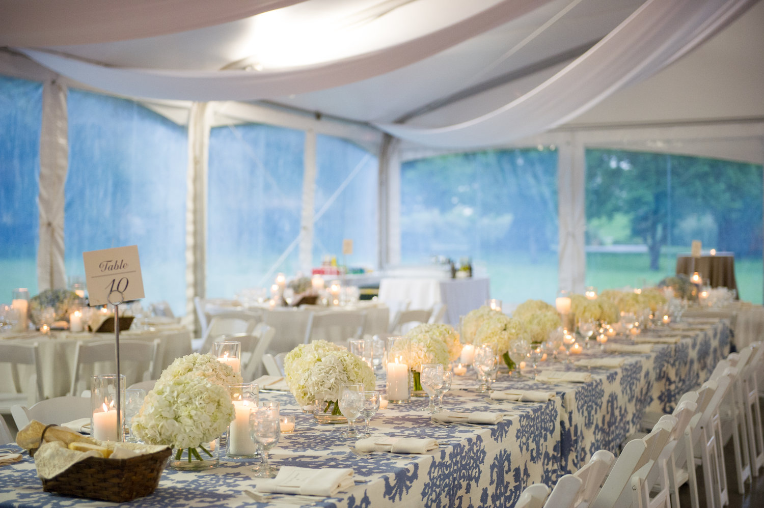White and blue table linens with white hydrangeas lining the table with tea lights and candles