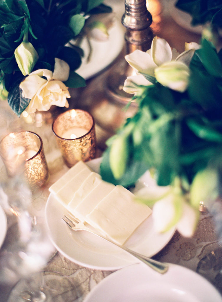 votive candles in mercury glass containers with gardenia flowers at a table place setting