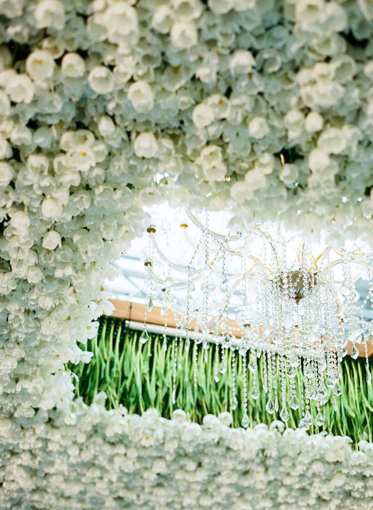 closeup of tulip chandelier ceiling, with white flowers and a crystal light fixture