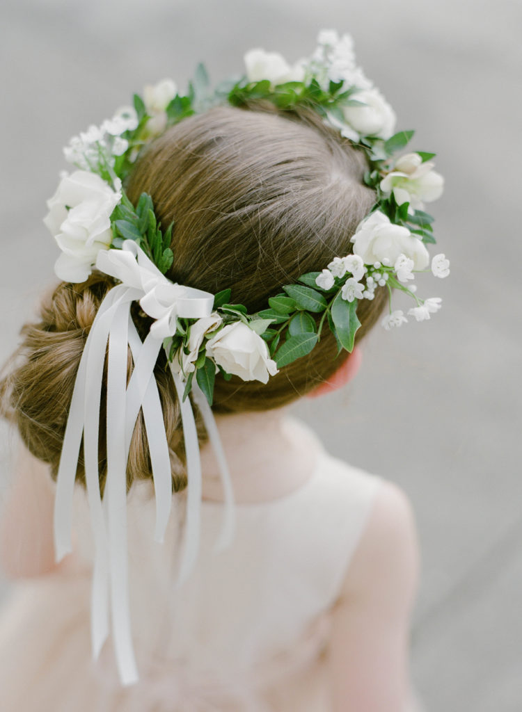 hair wreath with white ribbons and white flowers and greenery on a flower girls head